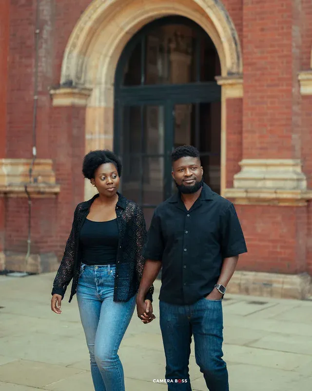 A couple walking together outside a red brick entrance. CameraBoss portfolio: Tomilayo Prewedding London.
