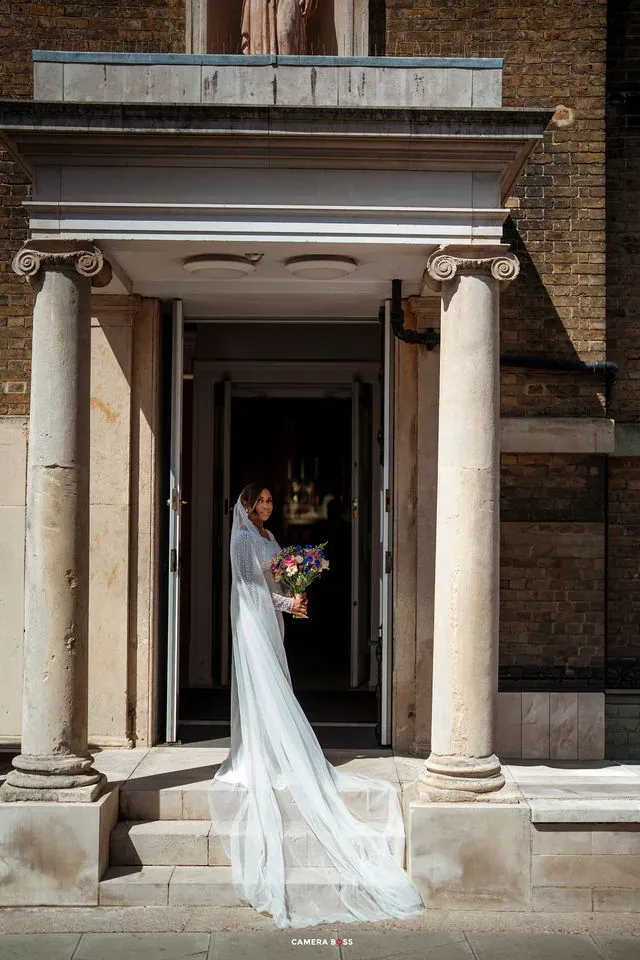 The bride standing in the doorway of a stone building. CameraBoss portfolio: Cynthia and Oswaldo.