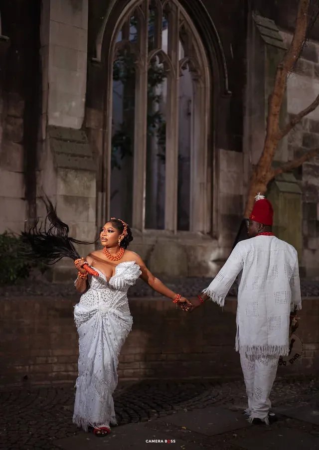 A couple holding hands beside a stone entrance. CameraBoss portfolio: Korede Prewedding.