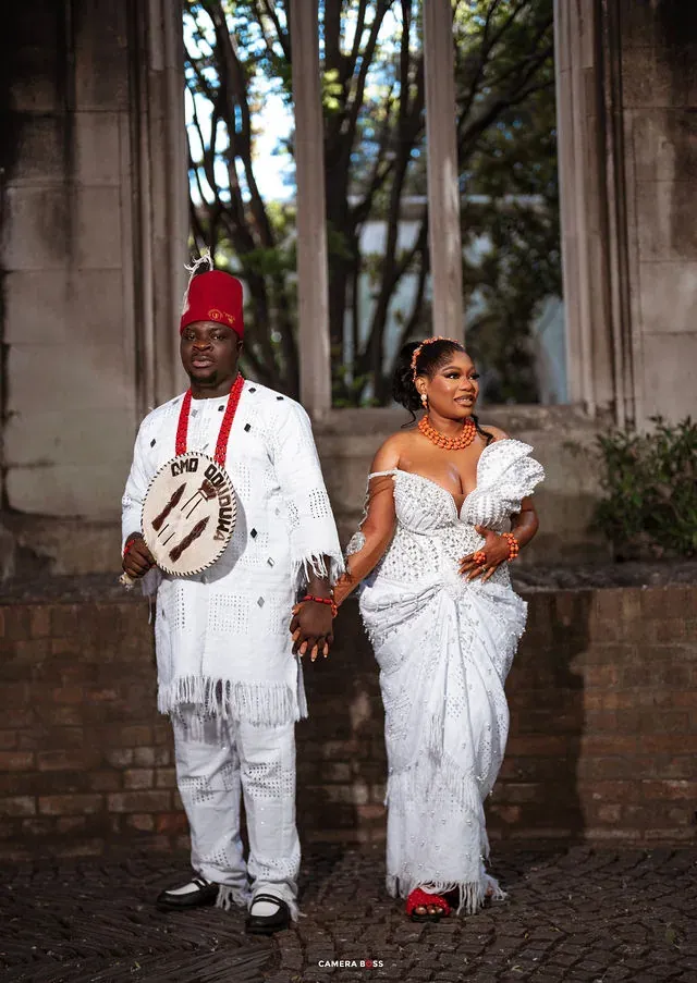 A full-length portrait of a couple beneath stone windows. CameraBoss portfolio: Korede Prewedding.