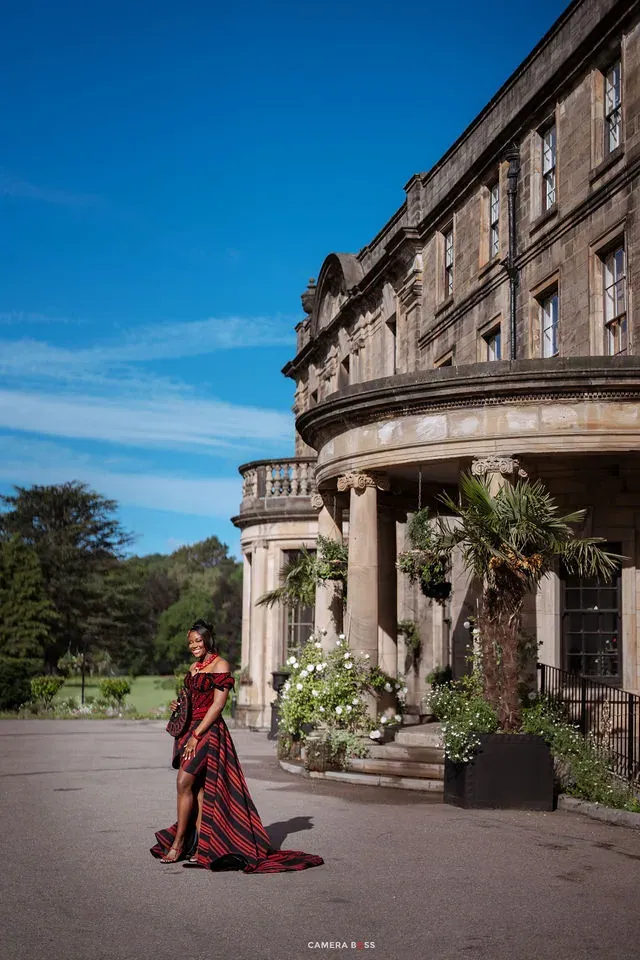 Jo outside a stone building in a red and black dress. CameraBoss portfolio: Jo and Jonny.
