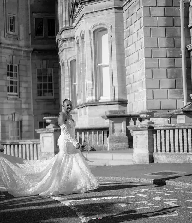 Remi and her train outside a stone building in black and white