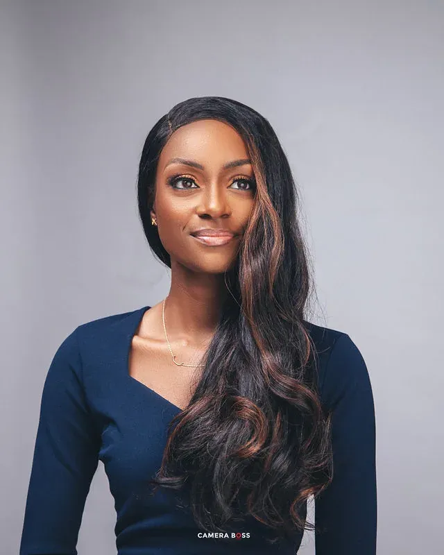 Studio headshot of a woman in a navy dress against a grey background