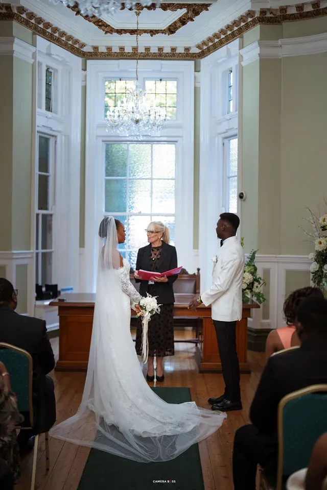 A wide ceremony photograph with Remi’s veil behind her