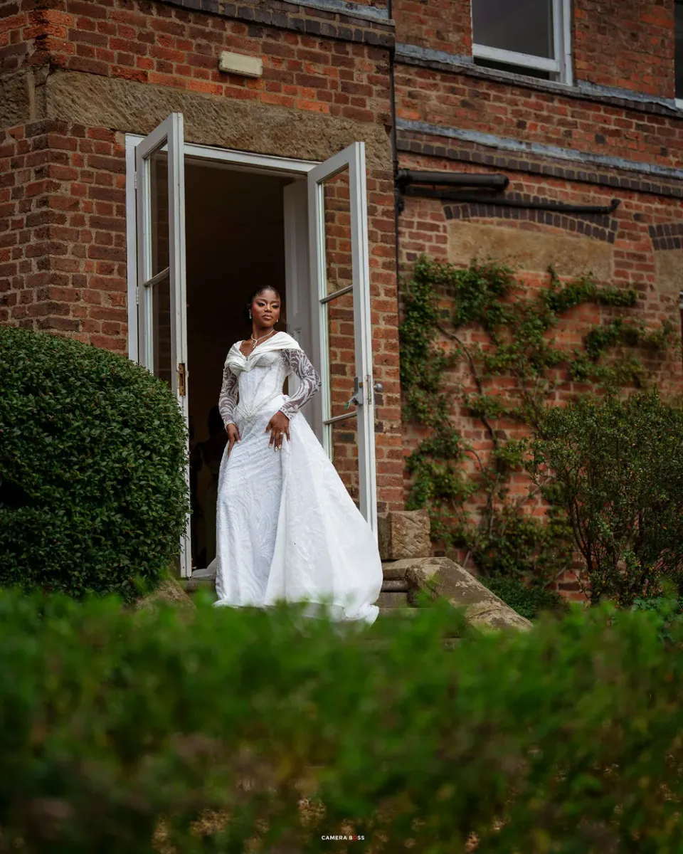 Helen standing in her wedding dress at the open doorway of Shottle Hall