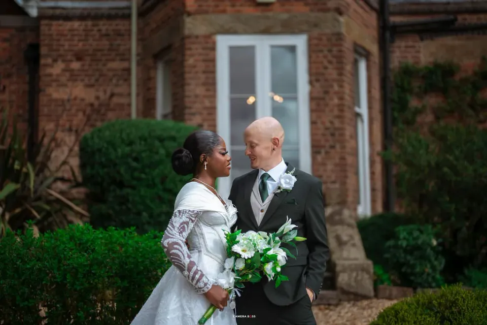 Helen and Jack together with their bouquet outside the brick house at Shottle Hall
