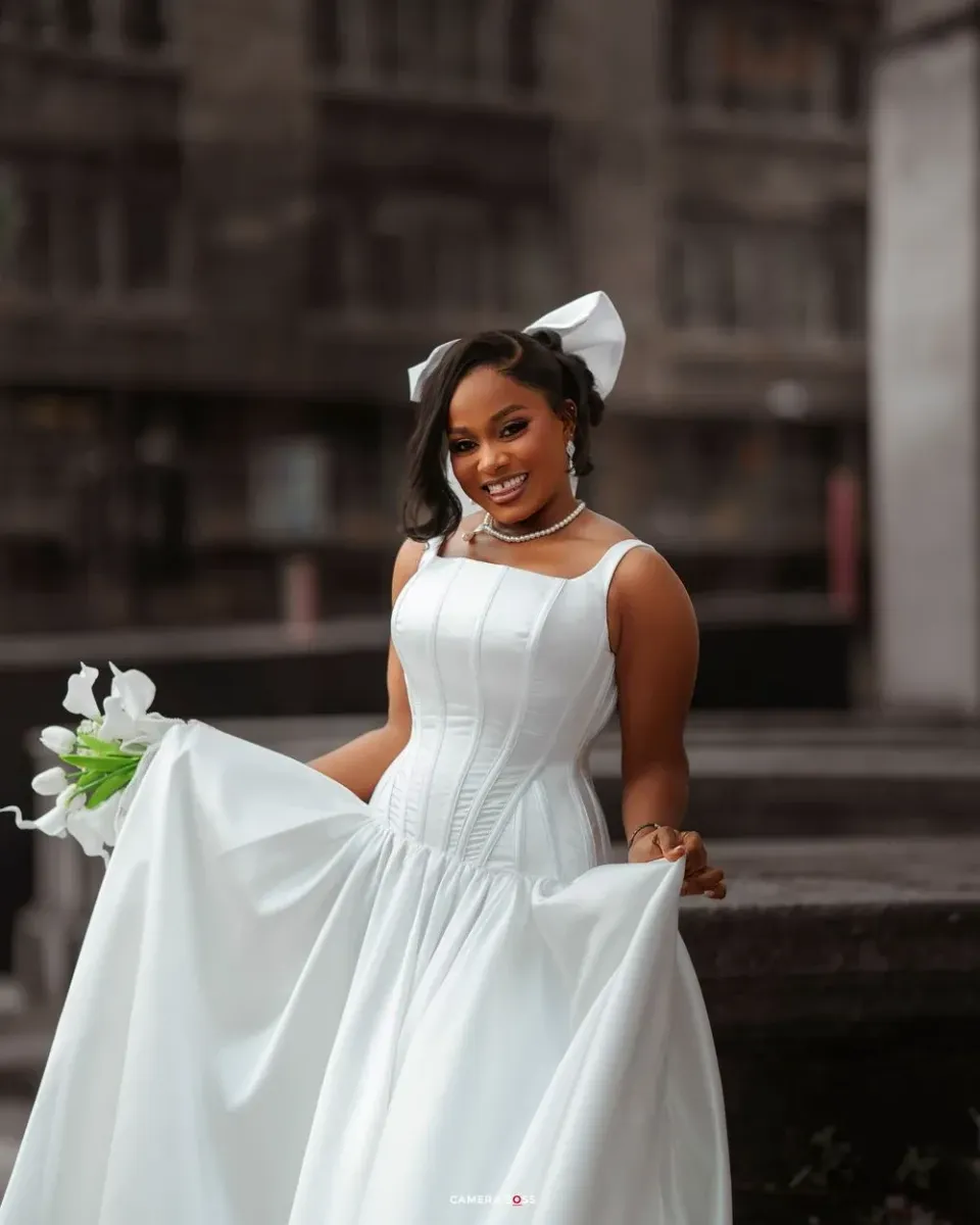 A person in a flowing white dress twirls and poses gracefully in an urban setting.