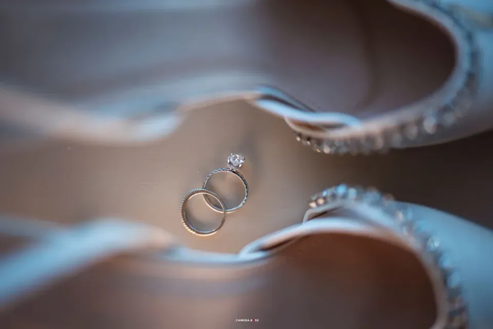 Wedding rings photographed between the bridal shoes